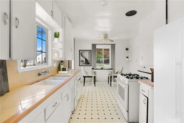 a large white kitchen with a sink and living room view