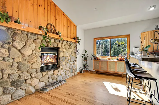 a kitchen with stainless steel appliances kitchen island granite countertop a refrigerator a stove top oven and a dining table with wooden floor