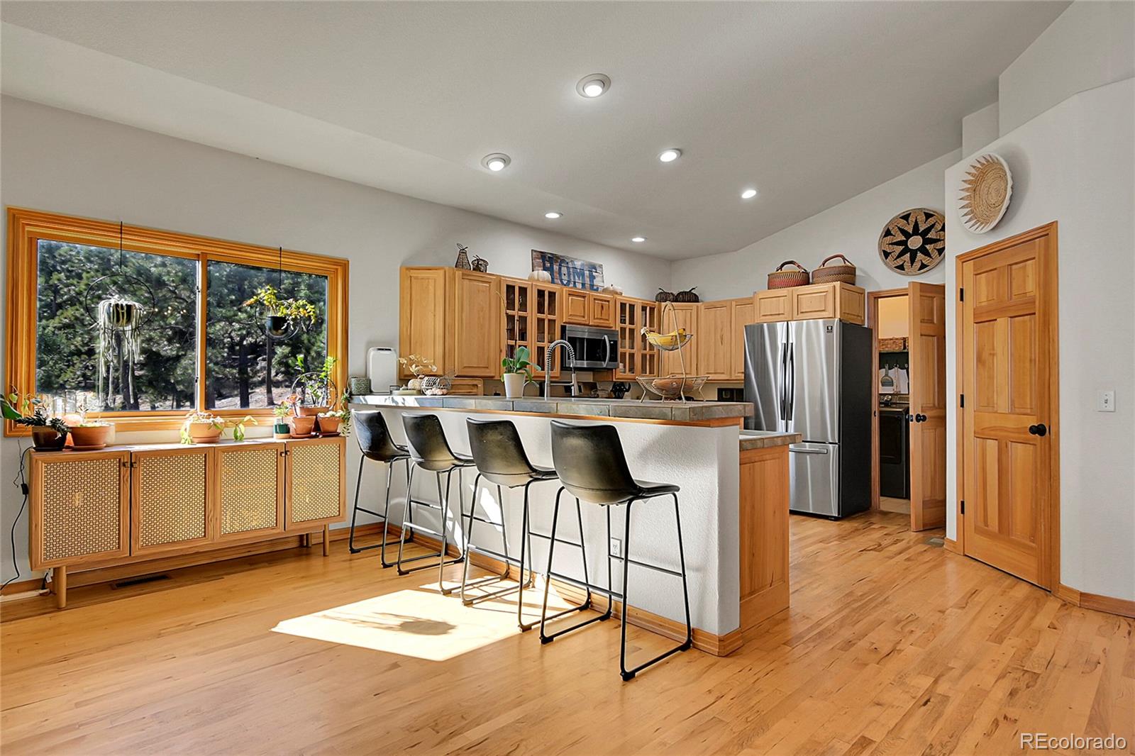 13382 Riley Peak Road Conifer, CO 80433 - Photo 10 of 25 a kitchen with stainless steel appliances kitchen island granite countertop a refrigerator a stove top oven and a dining table with wooden floor