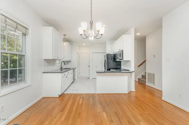 a large kitchen with kitchen island a white counter space a sink stainless steel appliances and cabinets