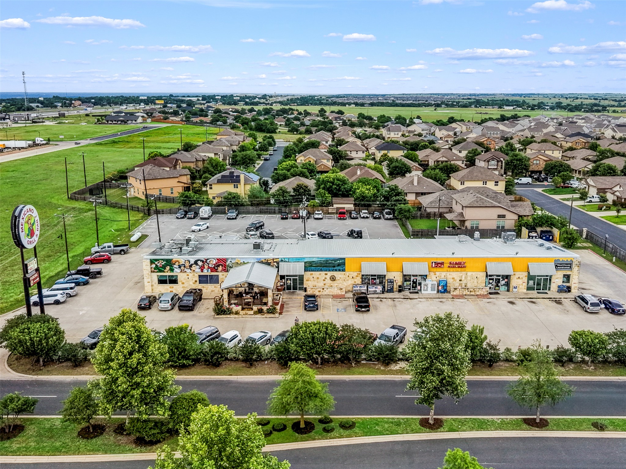 213 Ibis Falls Loop Jarrell, TX 76537 - Photo 35 of 37 A vibrant commercial building anchors a bustling neighborhood, offering diverse retail options.