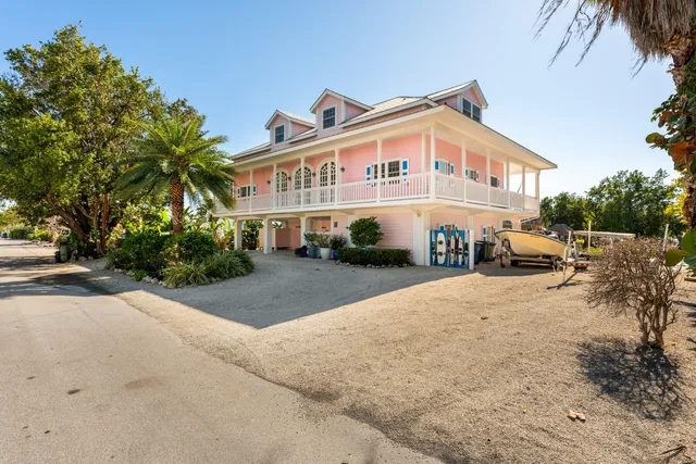 a view of a white house with a yard and palm trees