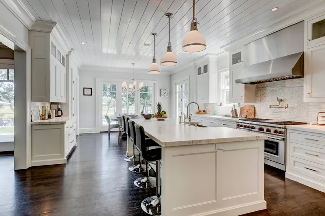 a kitchen with stainless steel appliances a stove a sink dishwasher and a dining table with wooden floor