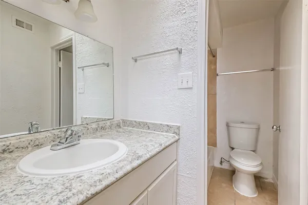 a bathroom with a granite countertop sink toilet and a mirror