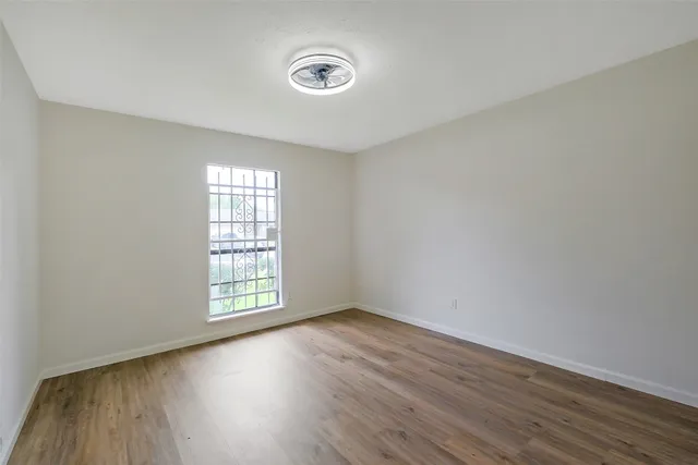 a view of an empty room with wooden floor and closet