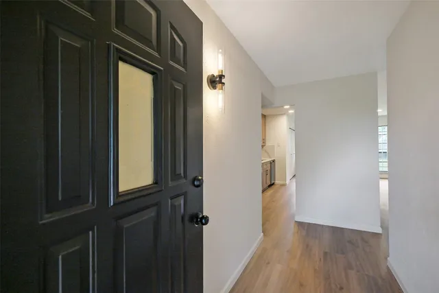 an empty room with wooden floor fireplace and windows