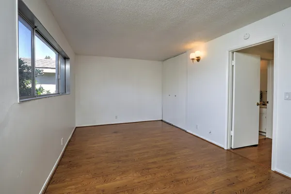 an empty room with wooden floor and windows