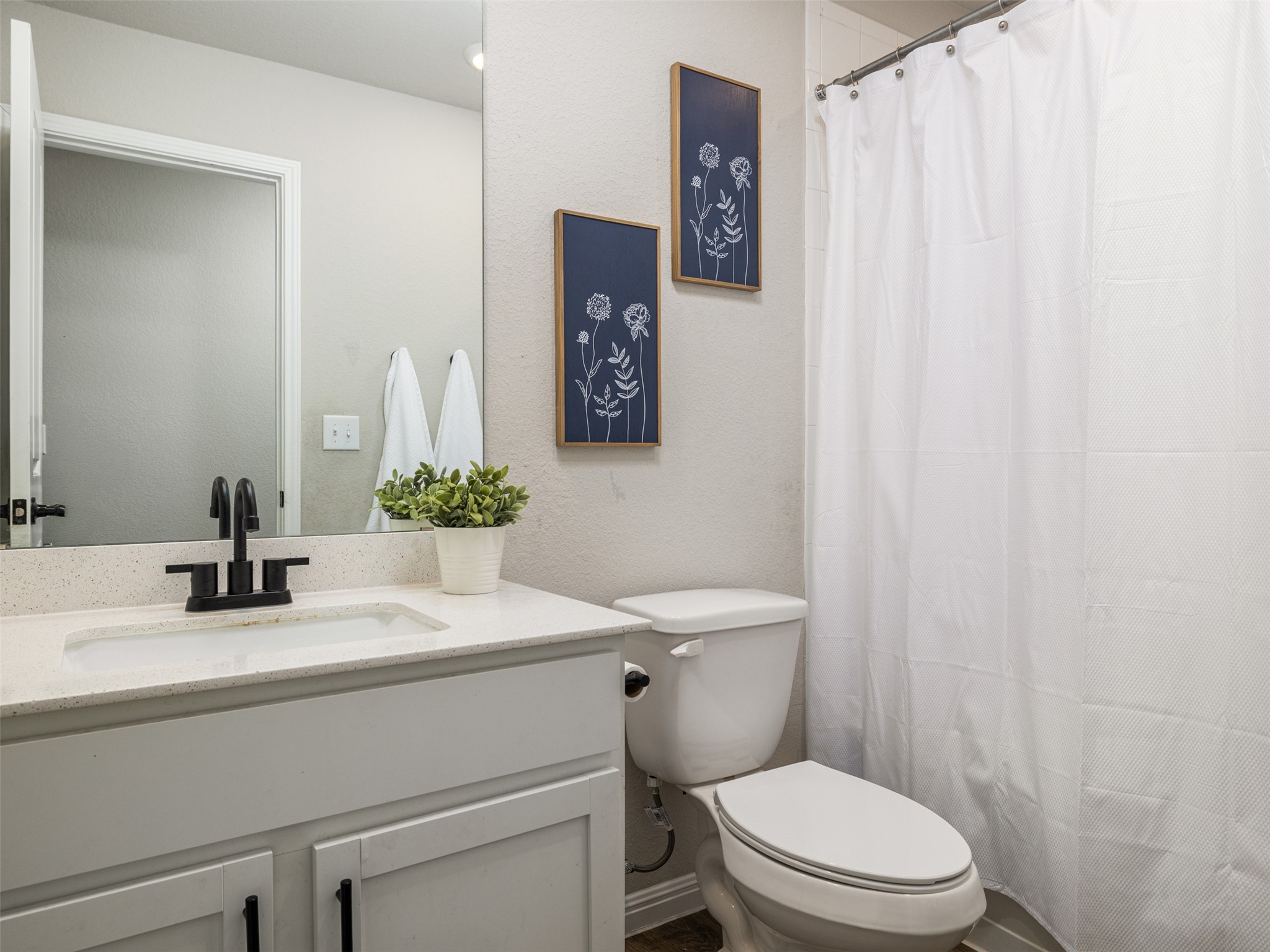 439 Hunter Loop Bertram, TX 78605 - Photo 18 of 23 A well-appointed bathroom features a sleek vanity, mirror, and a convenient shower with a privacy curtain.