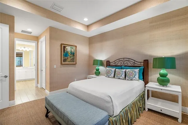 a bedroom with a bed a dresser and potted plant