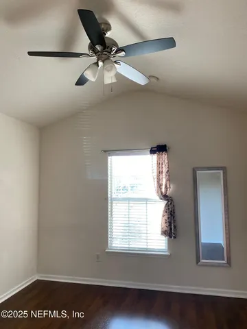 an empty room with wooden floor closet and windows