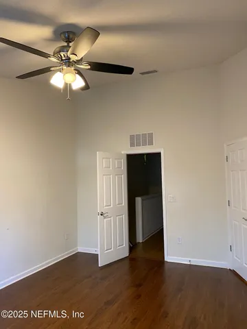 a view of a room with a chandelier fan and wooden floor