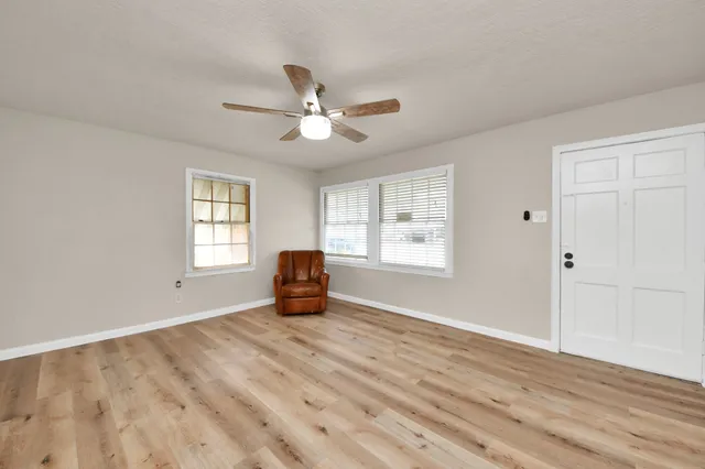 a view of an empty room with a window and wooden floor