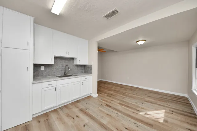 a kitchen with granite countertop a stove a sink and white cabinets with wooden floor