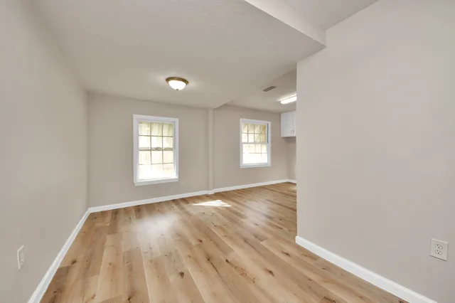 an empty room with wooden floor and windows