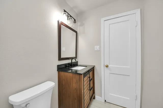 a bathroom with a granite countertop toilet sink and mirror