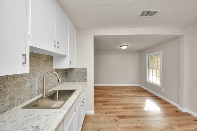 a kitchen with granite countertop a sink stove and cabinets