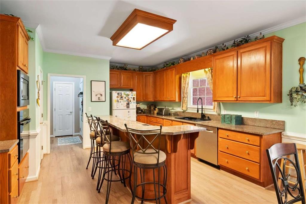 2055 Smyrna Road Southwest Conyers, GA 30094 - Photo 14 of 37 a kitchen with stainless steel appliances granite countertop a stove a refrigerator a sink dishwasher and a dining table with wooden floor