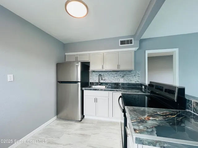 a kitchen with granite countertop a sink cabinets and stainless steel appliances