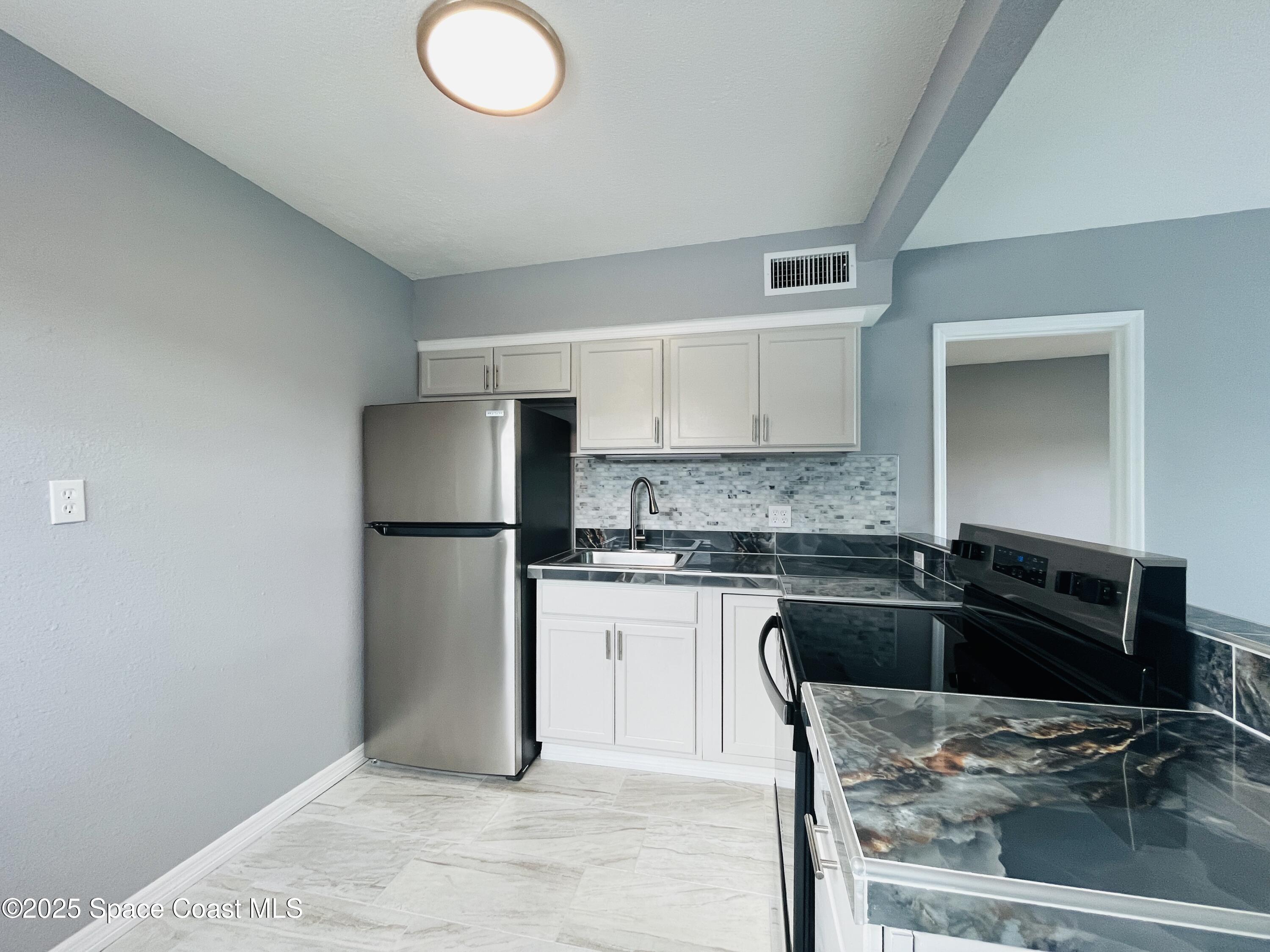 402 Adams Avenue, Unit E Cape Canaveral, FL 32920 - Photo 4 of 8 a kitchen with granite countertop a sink cabinets and stainless steel appliances