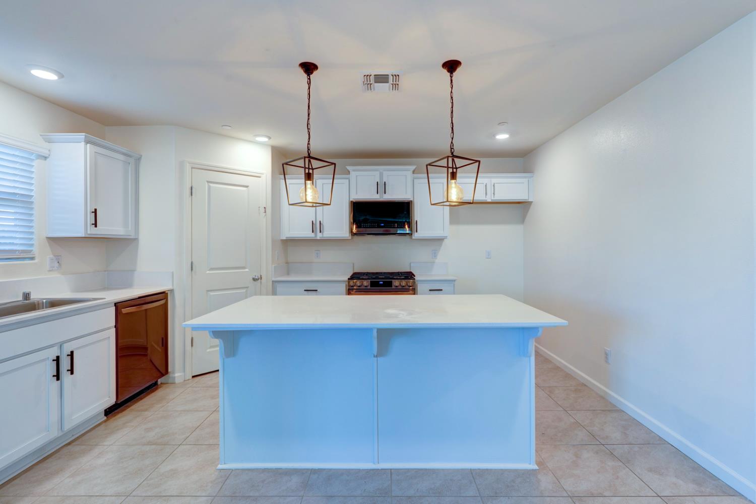 753 Heitz Way Merced, CA 95348 - Photo 23 of 70 a kitchen with a stove a sink and chandelier