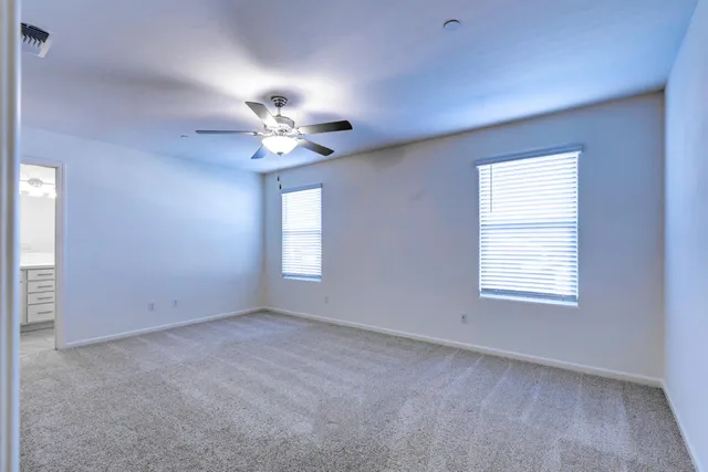 an empty room with windows and fan