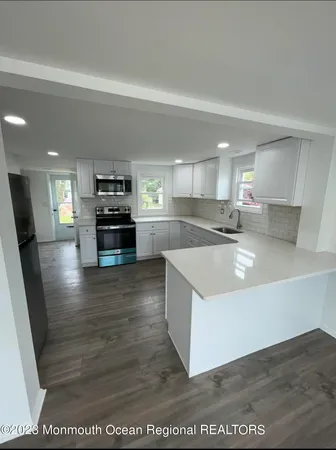 a large kitchen with stainless steel appliances granite countertop a large counter top a stove a sink and a refrigerator