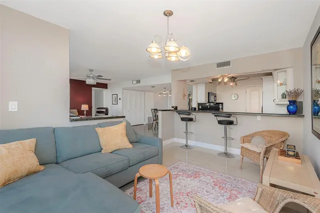 a living room with furniture a kitchen view and a chandelier