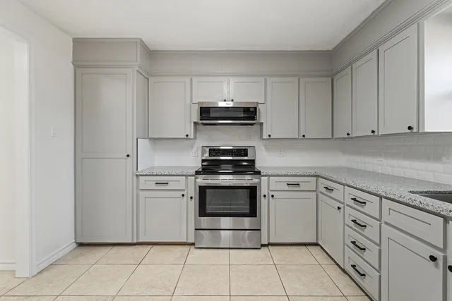a kitchen with white cabinets and appliances