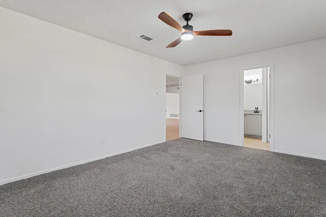 an empty room with ceiling fan and window