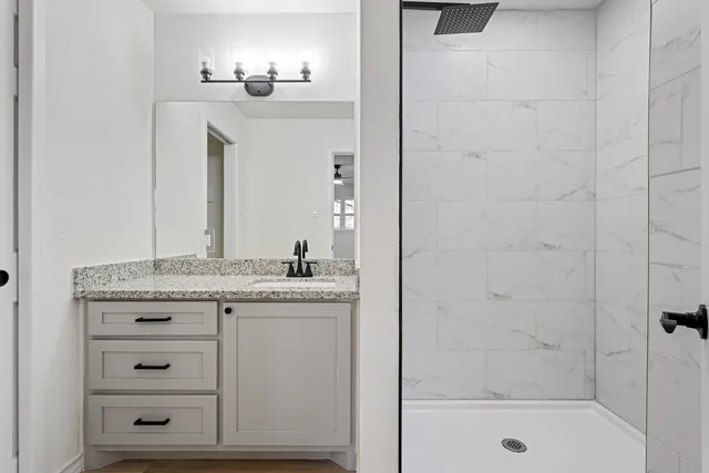 a bathroom with a granite countertop sink a toilet and shower