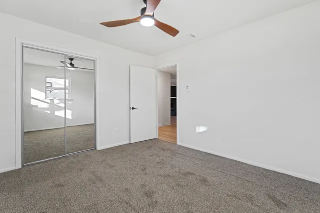 an empty room with closet and a chandelier fan