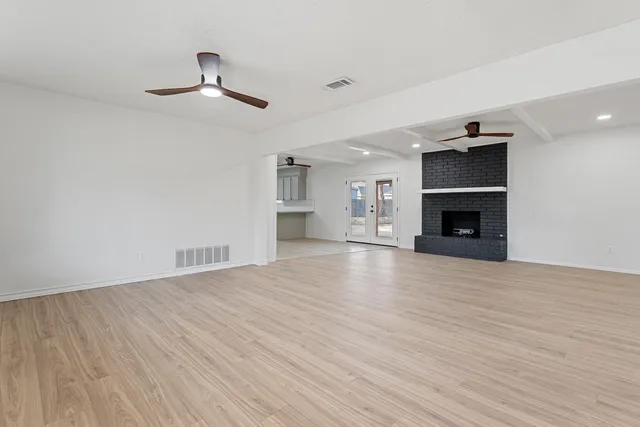 an empty room with wooden floor fireplace and windows