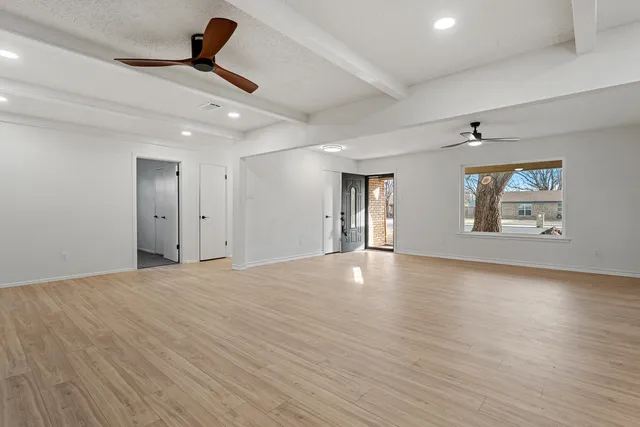 a view of an empty room with a window and wooden floor