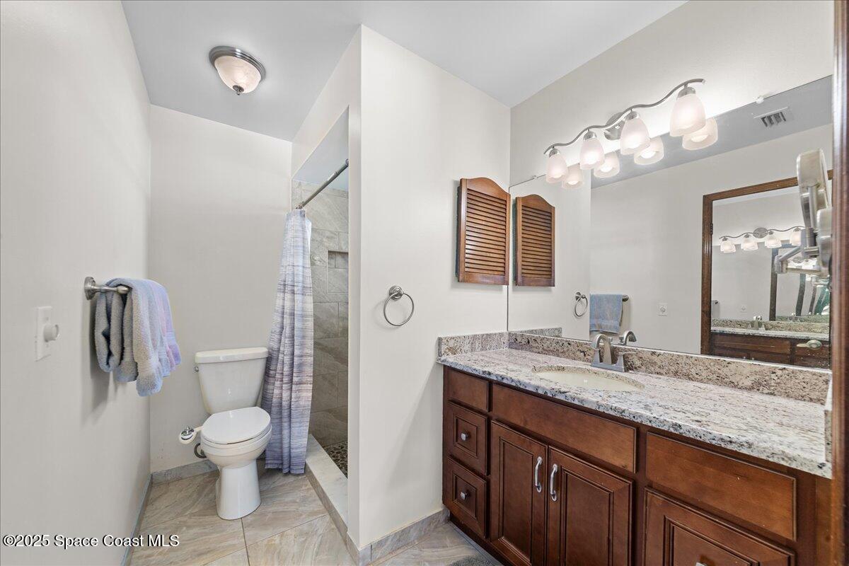 257 Avens Road Northeast Palm Bay, FL 32907 - Photo 19 of 52 a bathroom with a granite countertop toilet a sink and a mirror