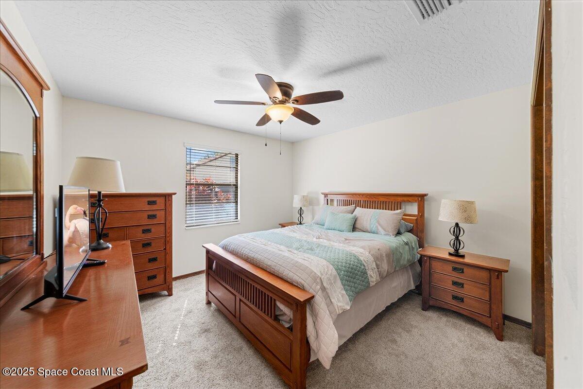 257 Avens Road Northeast Palm Bay, FL 32907 - Photo 22 of 52 a bedroom with a bed and a flat tv screen on dresser