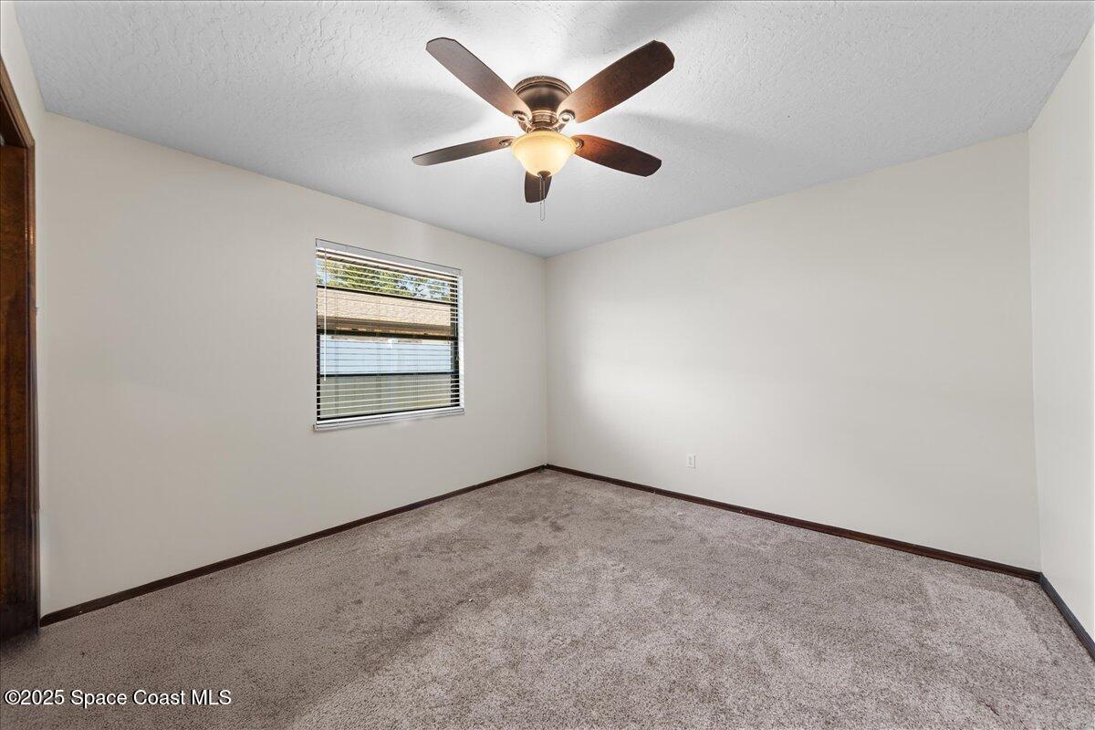 257 Avens Road Northeast Palm Bay, FL 32907 - Photo 24 of 52 an empty room with ceiling fan and windows