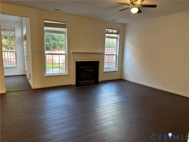 an empty room with wooden floor a ceiling fan and windows