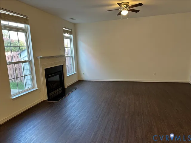 an empty room with wooden floor fireplace and windows