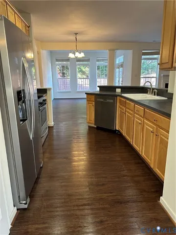 a large kitchen with stainless steel appliances a refrigerator a sink dishwasher a stove and white countertops with wooden floor