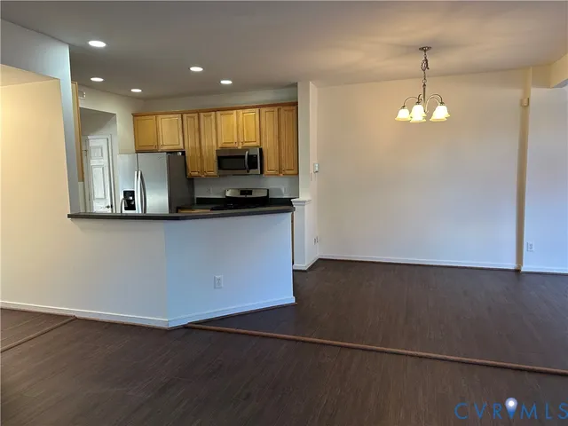 a view of a kitchen with kitchen island a sink wooden floor and a refrigerator