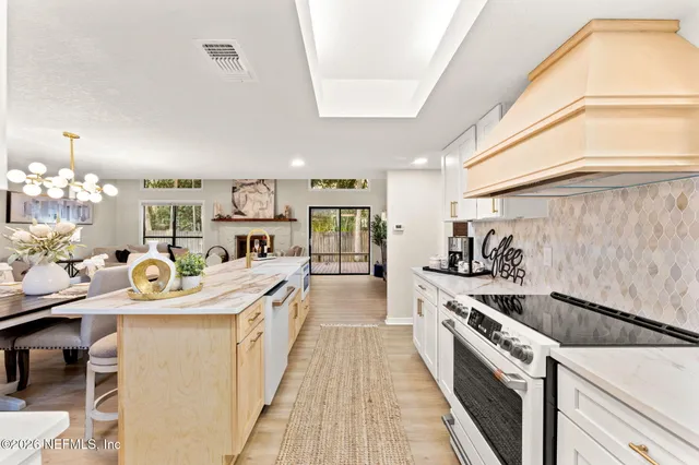 a large white kitchen with stainless steel appliances granite countertop a stove and a dining table