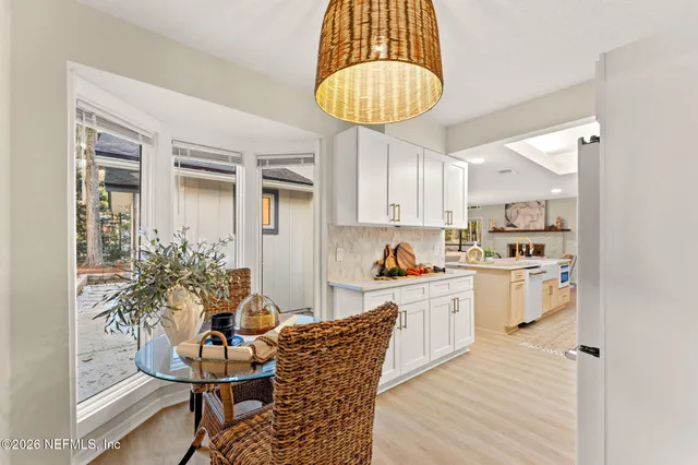 a kitchen with stainless steel appliances granite countertop a dining table chairs and white cabinets