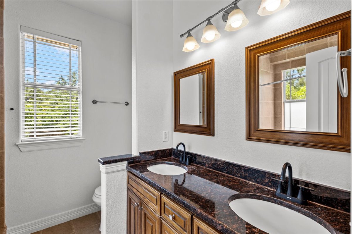 437 Balch Road Elgin, TX 78621 - Photo 14 of 37 Double vanity with rich granite counters and elegant wood-framed mirrors defines this well-appointed bathroom.