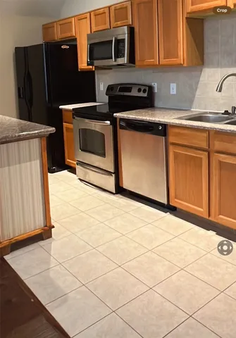 a kitchen with stainless steel appliances kitchen island granite countertop a refrigerator a stove a sink and dishwasher