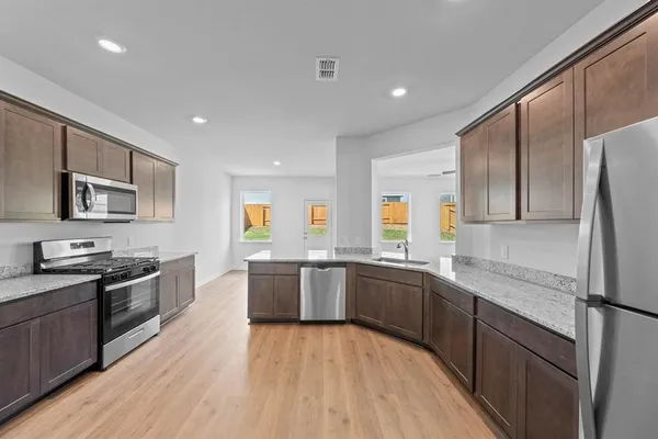 a large kitchen with granite countertop a large counter top stainless steel appliances and cabinets