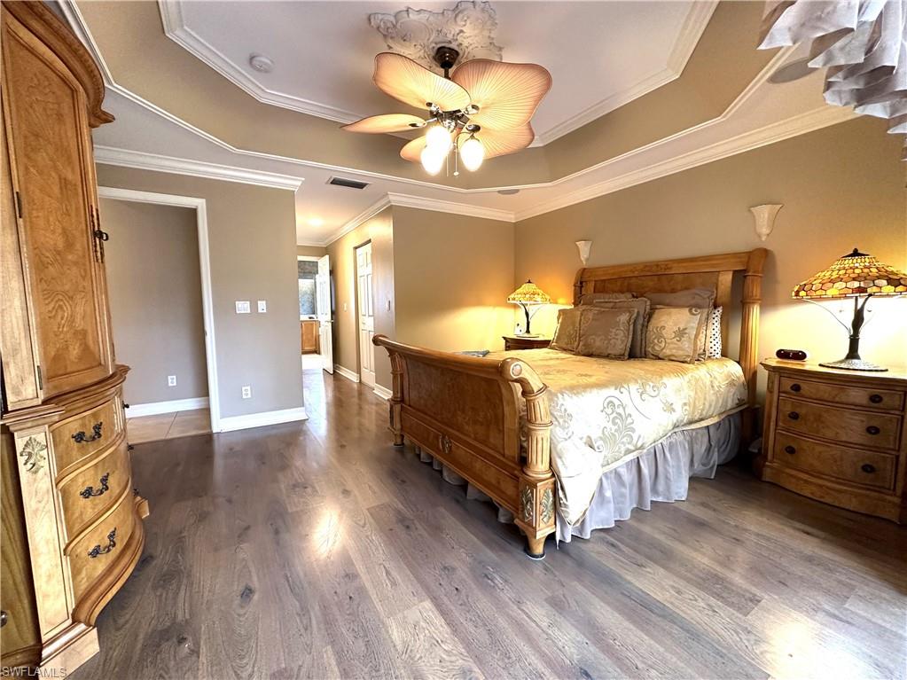 1357 Triandra Lane Naples, FL 34119 - Photo 14 of 40 a spacious bedroom with a bed and a chandelier