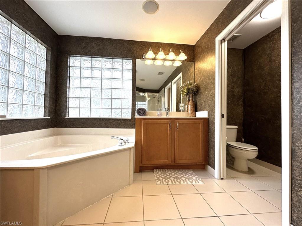 1357 Triandra Lane Naples, FL 34119 - Photo 18 of 40 a bathroom with a tub a toilet a sink and mirror