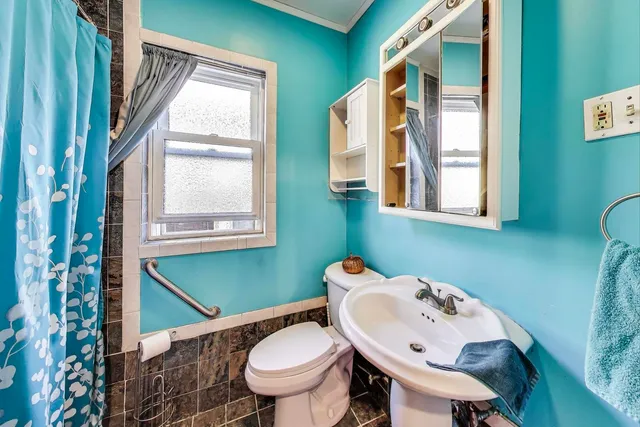 a bathroom with a sink mirror toilet and next to a window