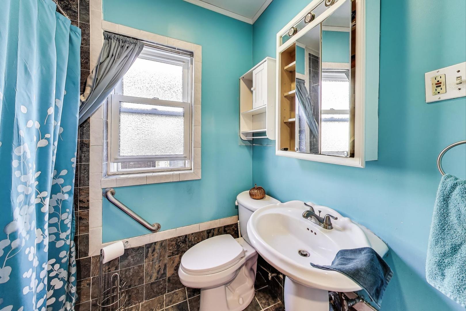 8346 South Aberdeen Street Chicago, IL 60620 - Photo 20 of 26 a bathroom with a sink mirror toilet and next to a window