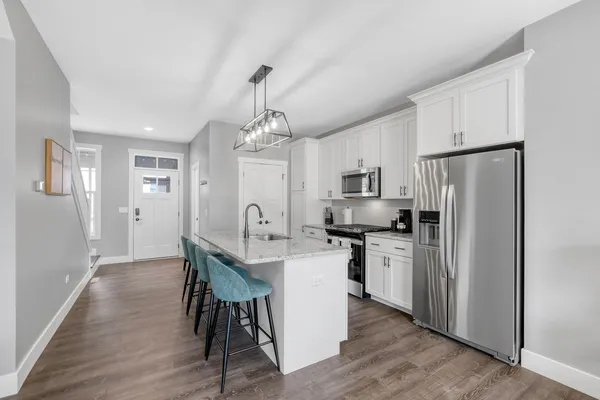 a kitchen with stainless steel appliances a dining table chairs refrigerator and cabinets